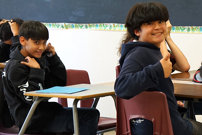 Two students smile from their desks