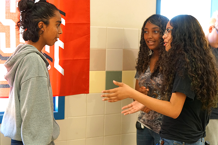 Three teen girls talk in the hallway