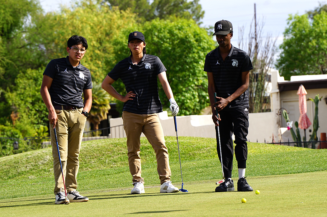 Three teen boys pose with their golf clubs