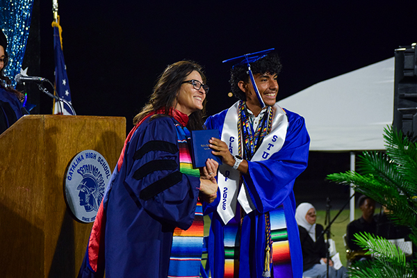 The principal poses with a graduate on stage