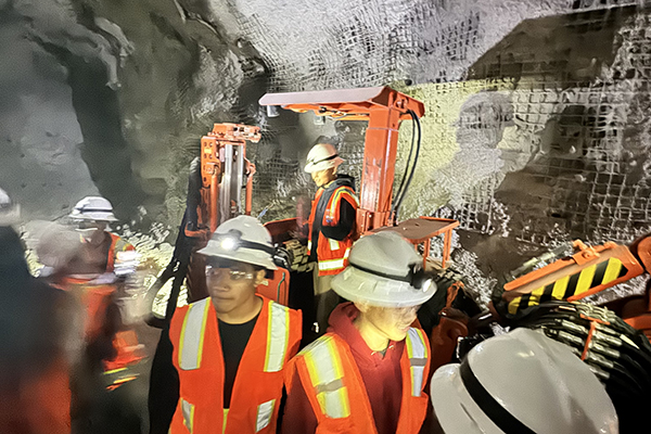 Students wearing hard hats and orange safety vests explore the mine