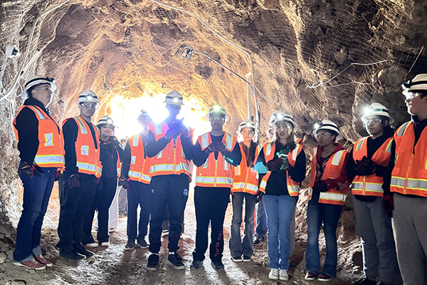 Students wearing hard hats and orange safety vests inside the mine