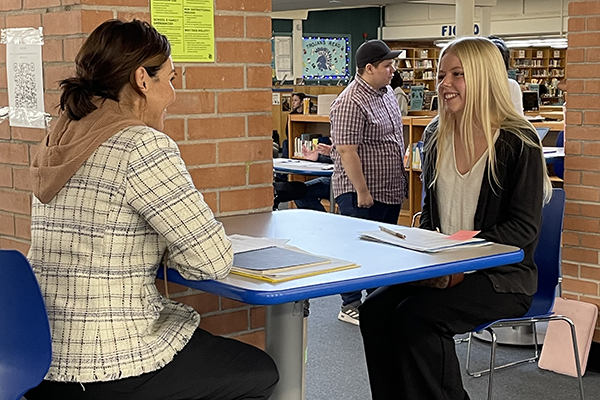 A woman, left, interviews an excited teen girl, right