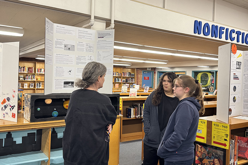 A teacher talks to two of her students about their science fair project