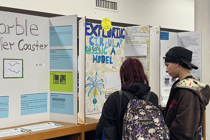 Two students look at a science fair poster
