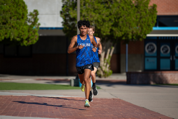 A line of teen boys wearing blue Catalina singlets run across the campus