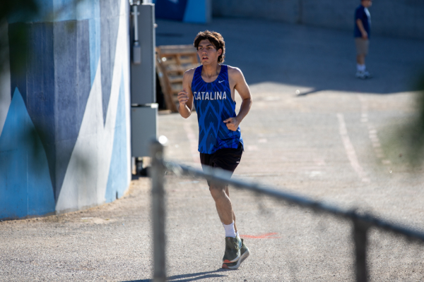 A teen boy in a blue Catalina singlet runs around the campus