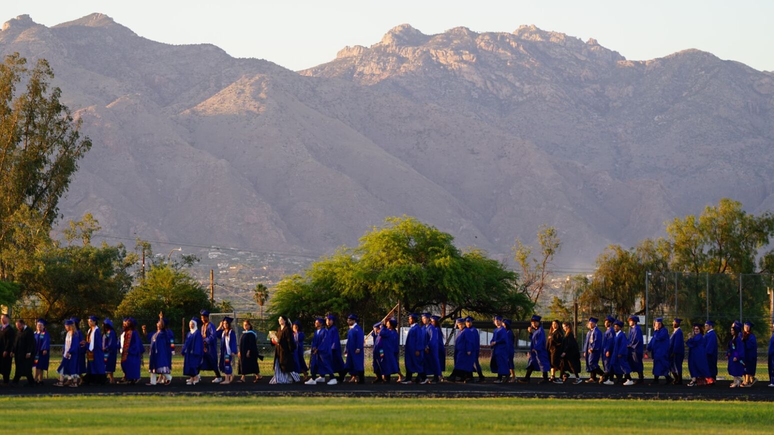 Catalina grads walk around the track with the Catalina Mountains in the background